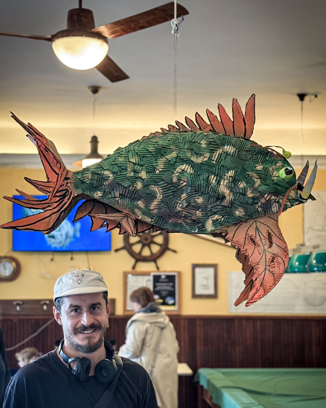Man with cardboard fish sculpture at Club Nautico